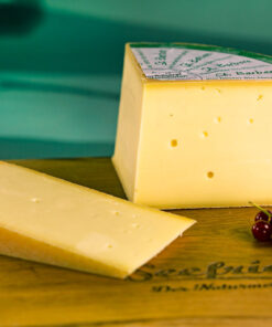 Ein Stück Käse St. Barbara vom Laib abgeschnitten auf Holzbrett